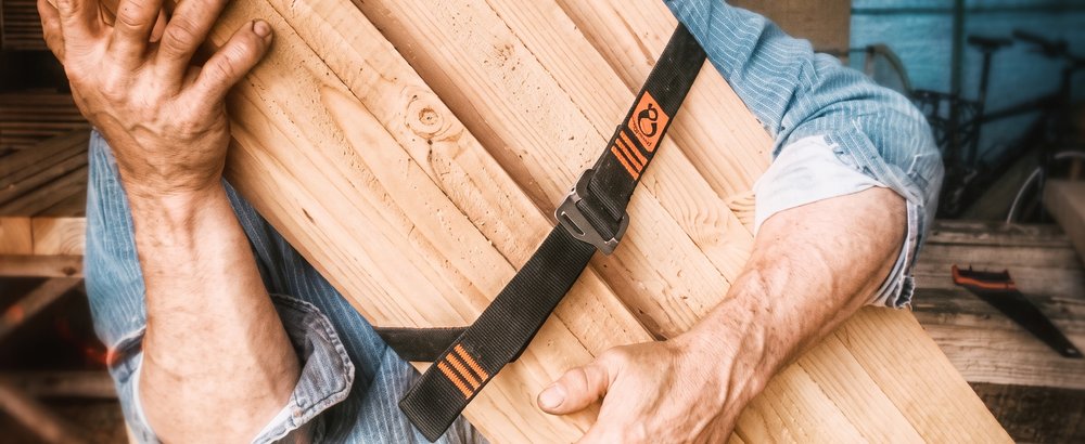 Charpentier portant des planches de bois maintenues par une sangle Tybelt