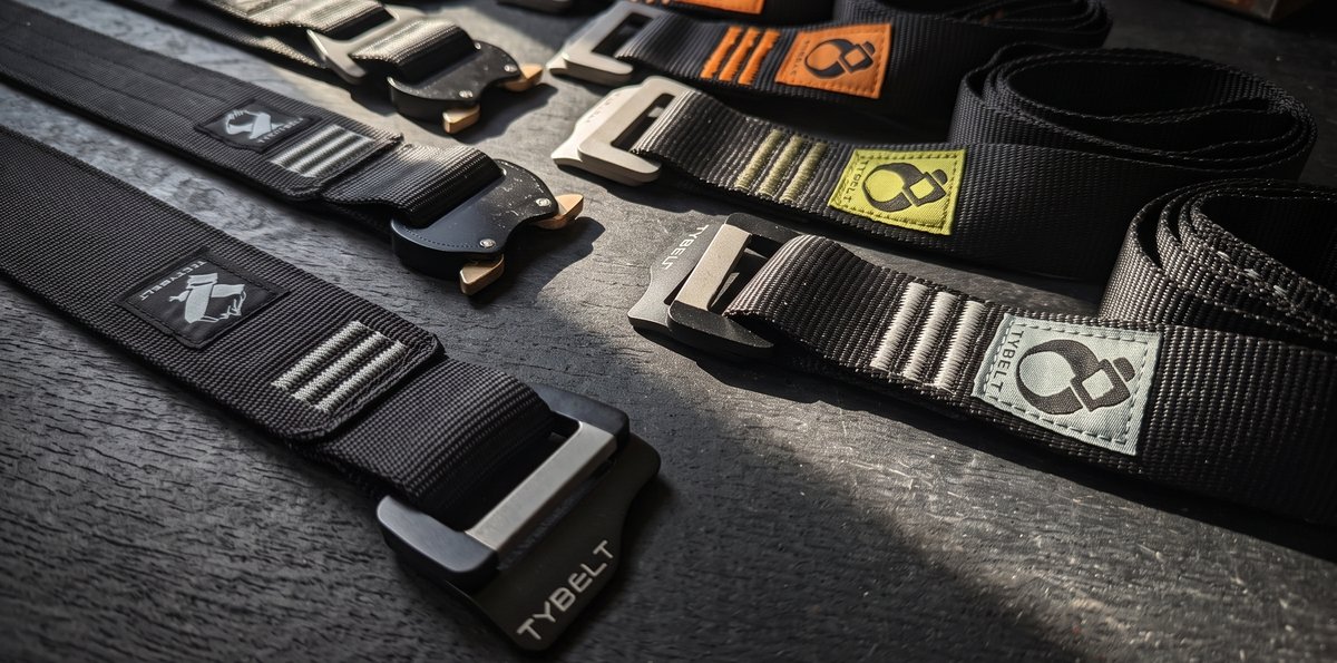 Ceintures Tybelt et Tactybelt avec leurs boucles et étiquettes tissées, posées côte à côte sur un plan sombre